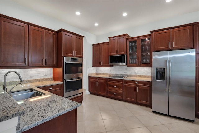 kitchen with appliances with stainless steel finishes, light stone countertops, sink, and backsplash