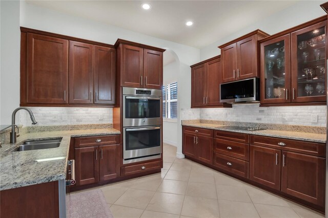 kitchen with light stone counters, sink, backsplash, and appliances with stainless steel finishes