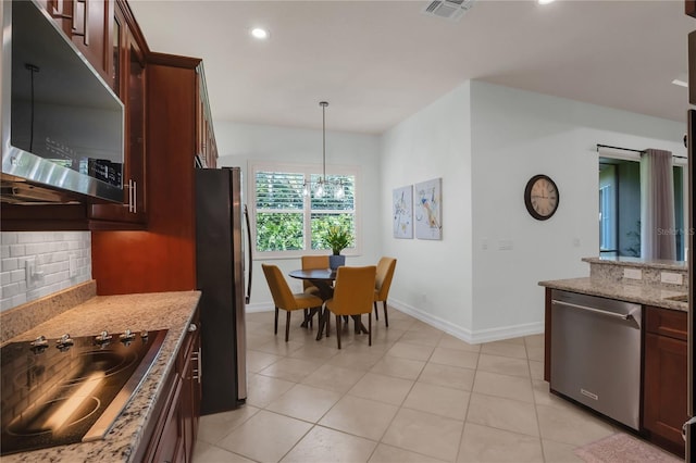 kitchen featuring light tile patterned floors, backsplash, hanging light fixtures, stainless steel appliances, and light stone countertops
