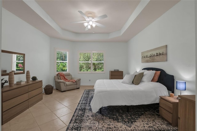 bedroom featuring light tile patterned floors, ceiling fan, and a tray ceiling