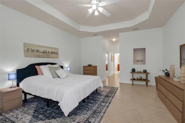tiled bedroom featuring a raised ceiling and ceiling fan
