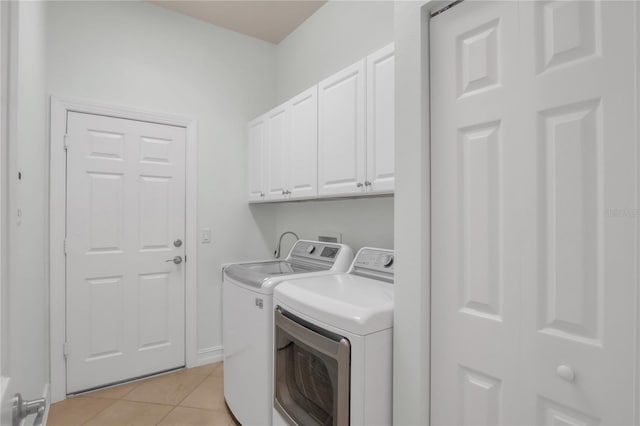 laundry area featuring washer and dryer, light tile patterned floors, and cabinets