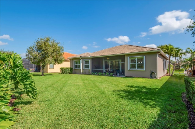 rear view of property featuring a sunroom and a lawn