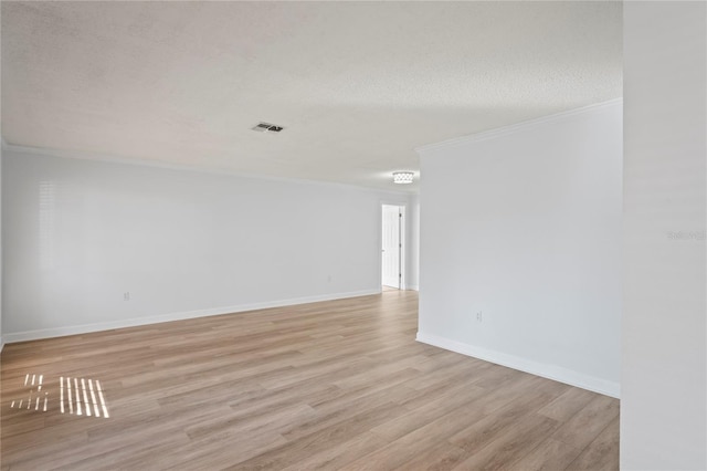 spare room featuring ornamental molding, light hardwood / wood-style floors, and a textured ceiling