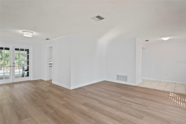 unfurnished room with ornamental molding, light wood-type flooring, and french doors