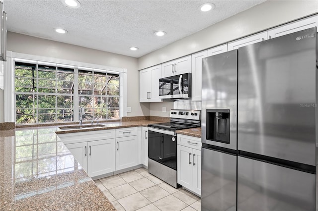 kitchen with sink, a textured ceiling, stainless steel appliances, and white cabinets