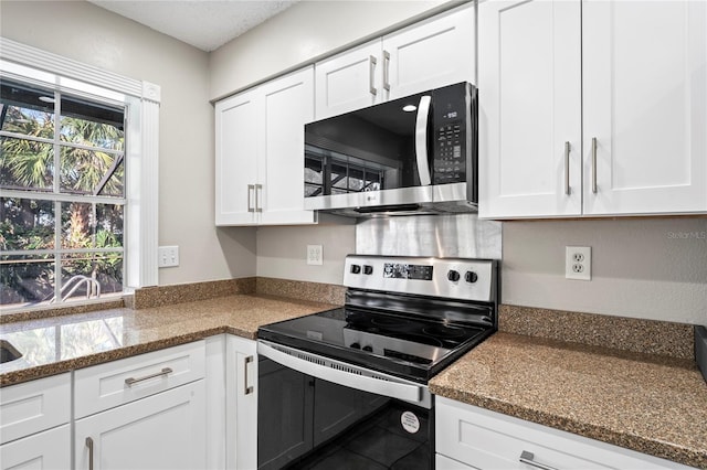 kitchen with white cabinetry, dark stone counters, and appliances with stainless steel finishes