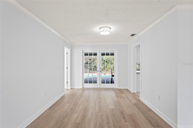 unfurnished room featuring ornamental molding, french doors, a textured ceiling, and light wood-type flooring