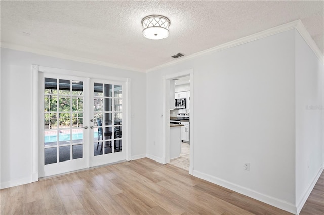 empty room with crown molding, light hardwood / wood-style flooring, french doors, and a textured ceiling