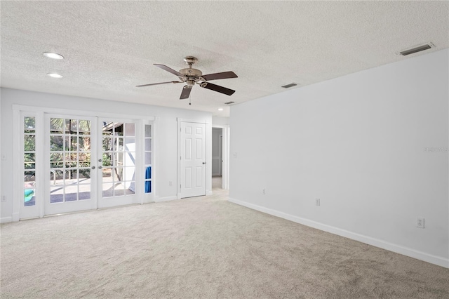 empty room with french doors, ceiling fan, carpet flooring, and a textured ceiling