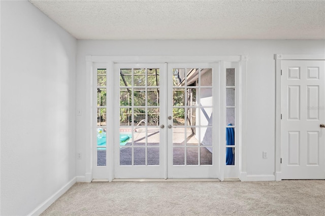 entryway with carpet floors, a textured ceiling, and french doors