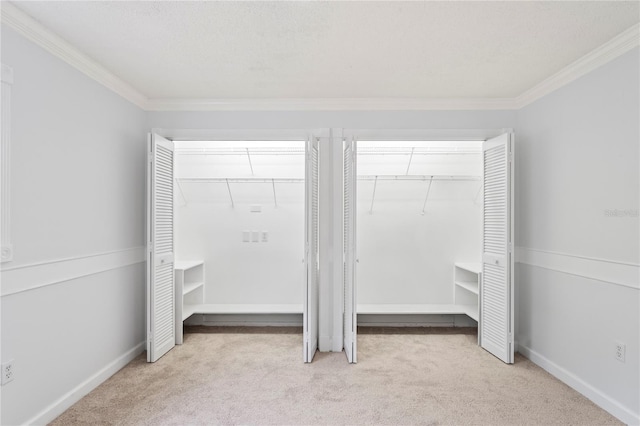 interior space with ornamental molding, a textured ceiling, light carpet, and two closets