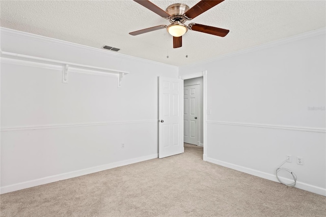 carpeted empty room with ceiling fan, ornamental molding, and a textured ceiling