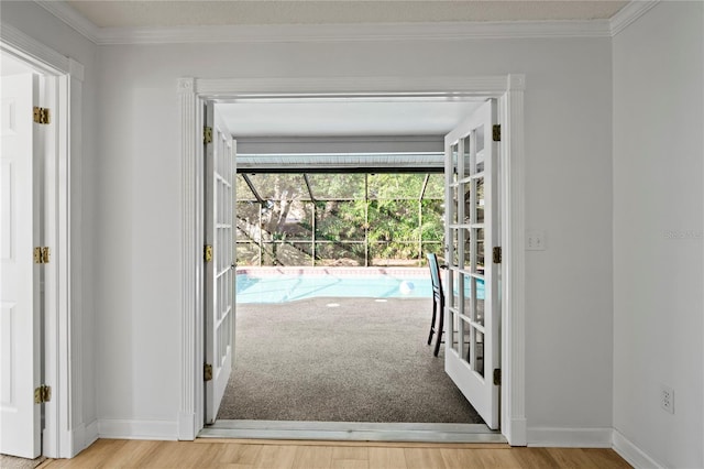 entryway with crown molding, light hardwood / wood-style floors, and french doors