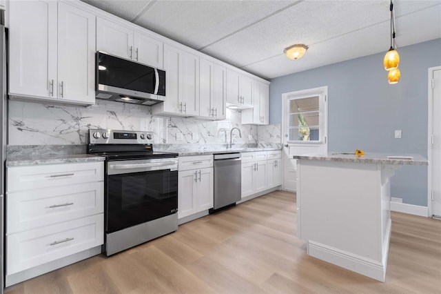 kitchen featuring white cabinetry, hanging light fixtures, stainless steel appliances, and light wood-type flooring