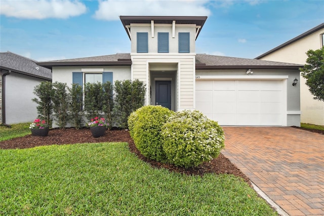 view of front of property with a garage, a front lawn, decorative driveway, and stucco siding