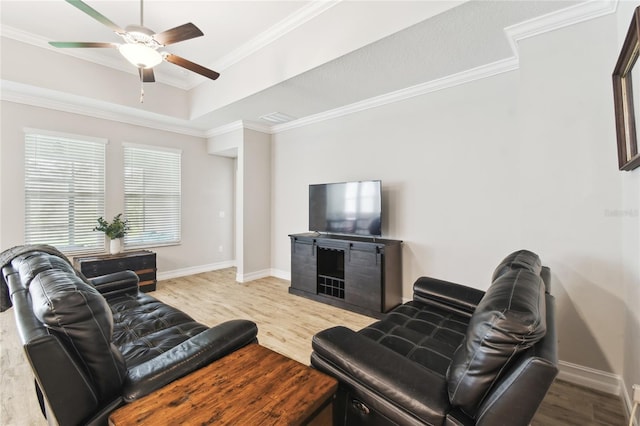 living area with ornamental molding, a raised ceiling, baseboards, and wood finished floors