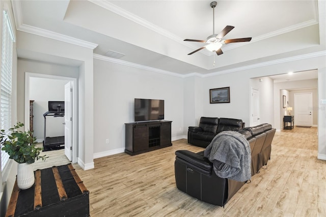 living room featuring a tray ceiling, crown molding, and light wood finished floors