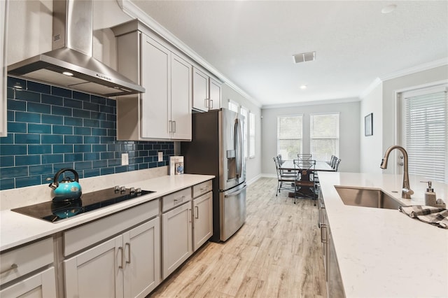 kitchen with visible vents, stainless steel fridge with ice dispenser, wall chimney exhaust hood, black electric cooktop, and a sink