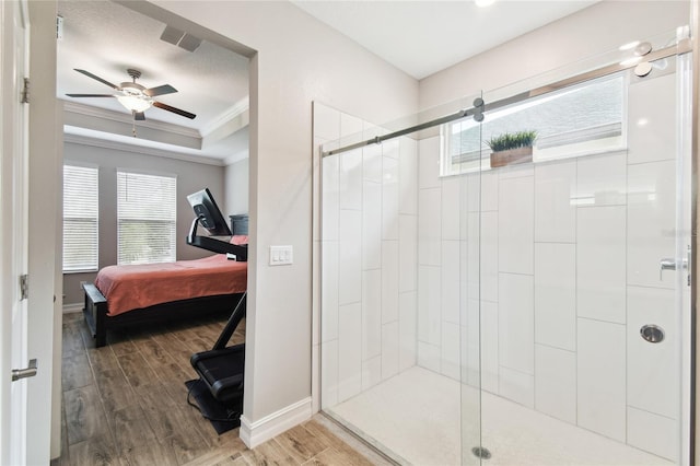 ensuite bathroom featuring ensuite bathroom, wood finished floors, a shower stall, a tray ceiling, and crown molding