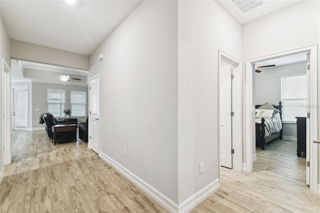 corridor featuring light wood finished floors, baseboards, and visible vents