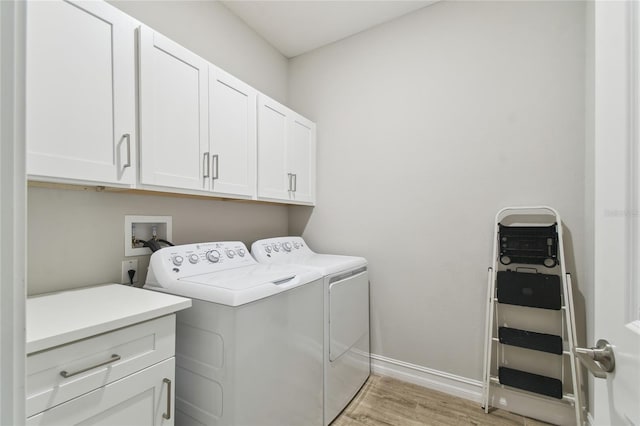 laundry area featuring washer and clothes dryer, light wood-type flooring, cabinet space, and baseboards