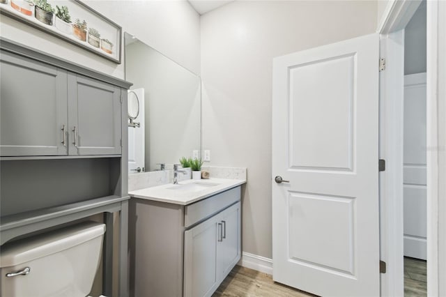 bathroom with toilet, wood finished floors, and vanity