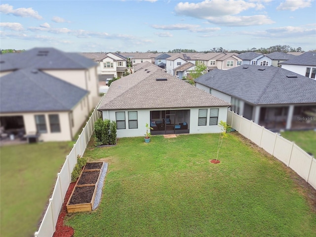 rear view of house featuring a lawn, a vegetable garden, a residential view, and a fenced backyard