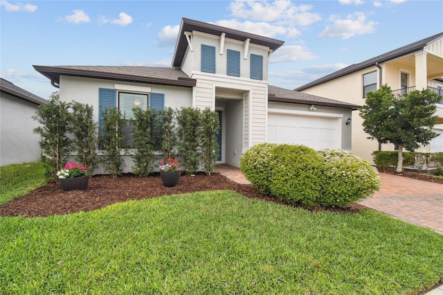 view of front of property with a front yard, decorative driveway, and an attached garage