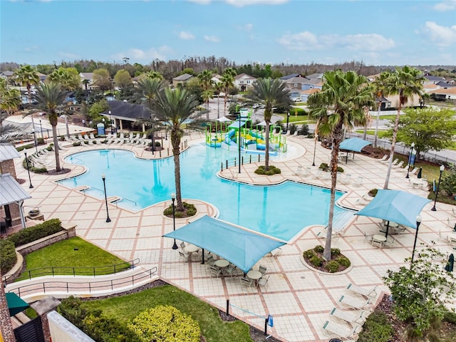 community pool with a patio, a residential view, fence, a water slide, and a water play area