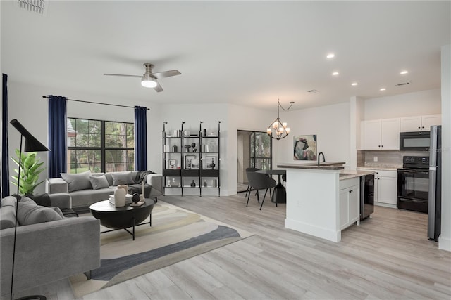 living room with wine cooler, sink, ceiling fan with notable chandelier, and light hardwood / wood-style floors