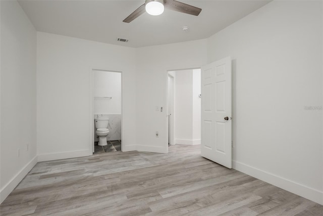 unfurnished bedroom with ensuite bathroom, ceiling fan, and light wood-type flooring