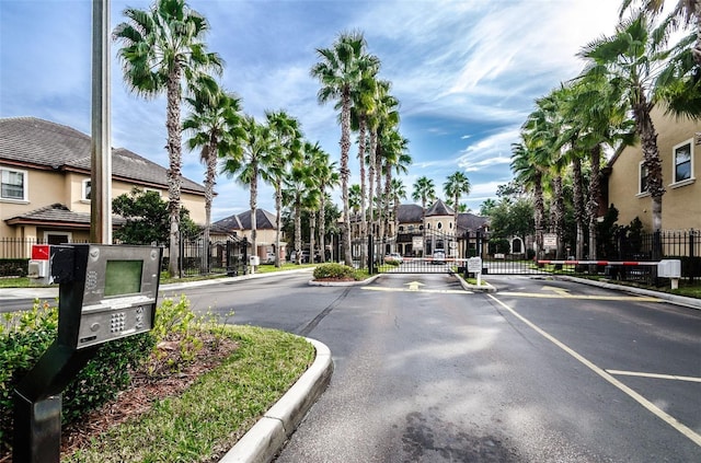 view of road with a residential view, a gate, a gated entry, and curbs