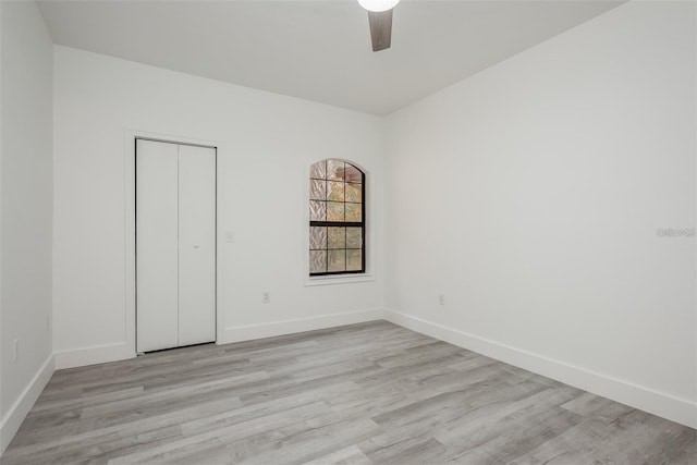 unfurnished bedroom featuring ceiling fan, light hardwood / wood-style floors, and a closet