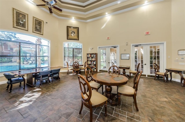 dining area with crown molding, ceiling fan, a high ceiling, french doors, and a raised ceiling