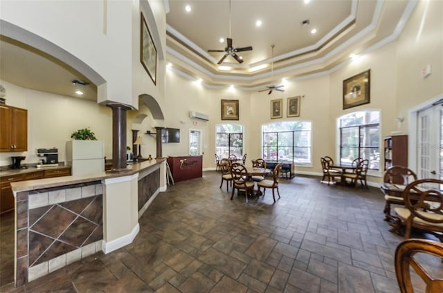 interior space with crown molding, ceiling fan, a towering ceiling, decorative columns, and white fridge