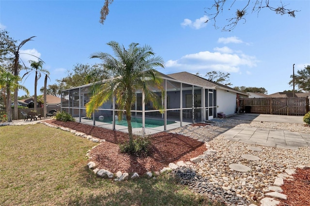 view of swimming pool featuring a yard, glass enclosure, and a patio area