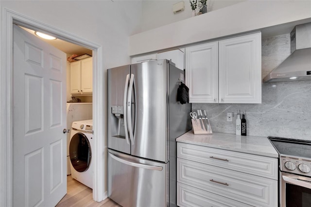 kitchen featuring white cabinetry, stainless steel appliances, decorative backsplash, washer / dryer, and wall chimney exhaust hood