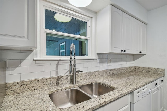 kitchen with sink, white cabinets, decorative backsplash, light stone counters, and white dishwasher