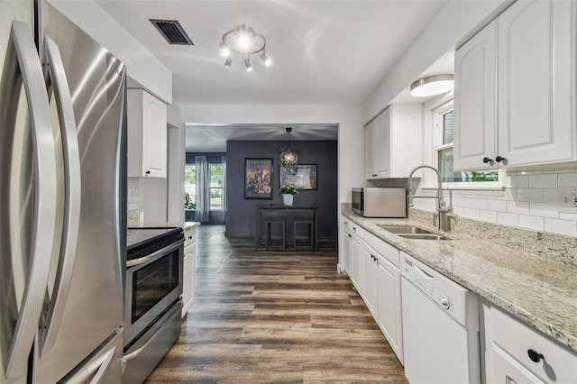 kitchen featuring sink, stainless steel appliances, tasteful backsplash, white cabinets, and decorative light fixtures