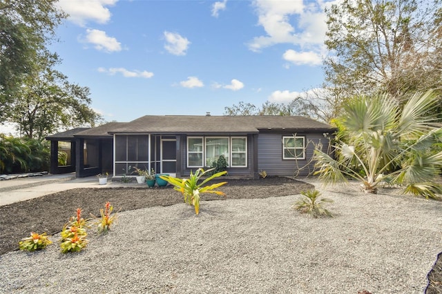 ranch-style house featuring a carport, driveway, and a sunroom