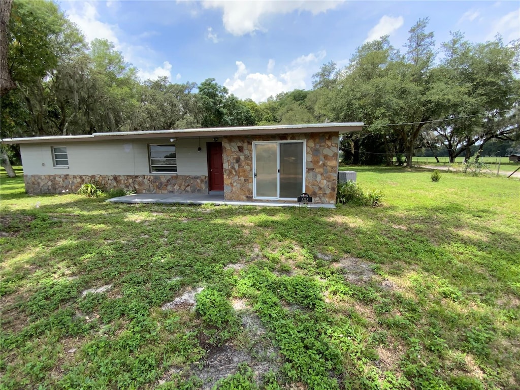 3223 Coats Rd, Zephyrhills, FL 33541 - view of front of house with stone siding, a patio area, and a front lawn