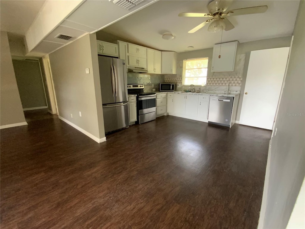 3223 Coats Rd, Zephyrhills, FL 33541 - kitchen with appliances with stainless steel finishes, under cabinet range hood, white cabinetry, backsplash, and a ceiling fan