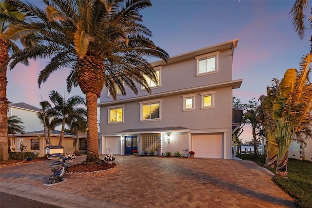 traditional-style house featuring decorative driveway, an attached garage, and stucco siding