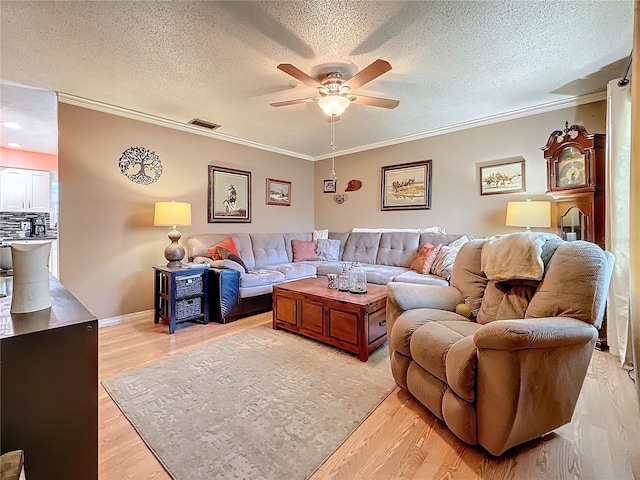 living room with crown molding, a textured ceiling, ceiling fan, and light hardwood / wood-style flooring