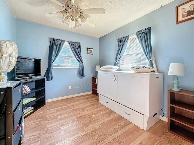 bedroom with ceiling fan, light hardwood / wood-style flooring, and a textured ceiling