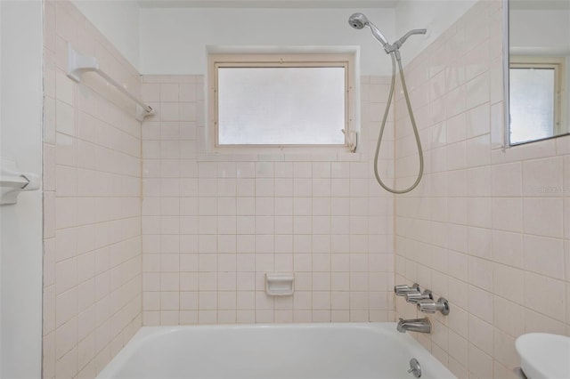 bathroom with tiled shower / bath combo and toilet