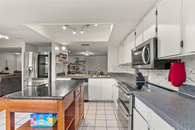 kitchen featuring sink, a center island, a raised ceiling, stainless steel appliances, and white cabinets