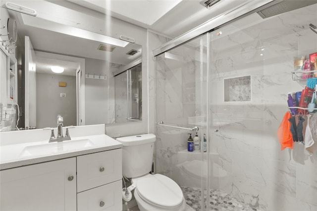 bathroom featuring vanity, a shower with shower door, and toilet