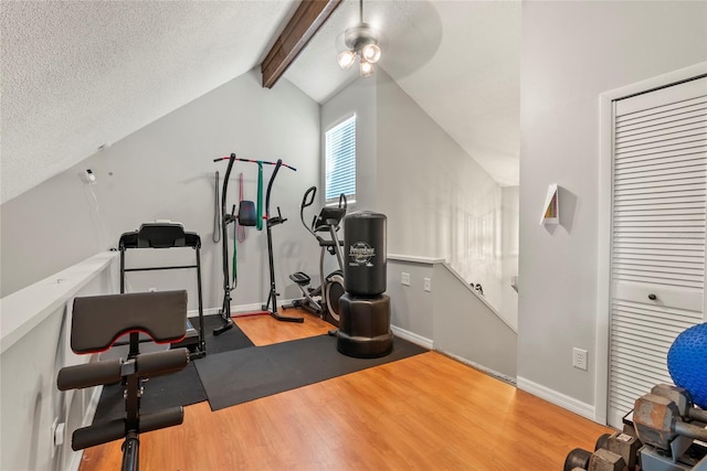 exercise room with wood-type flooring, vaulted ceiling, and a textured ceiling